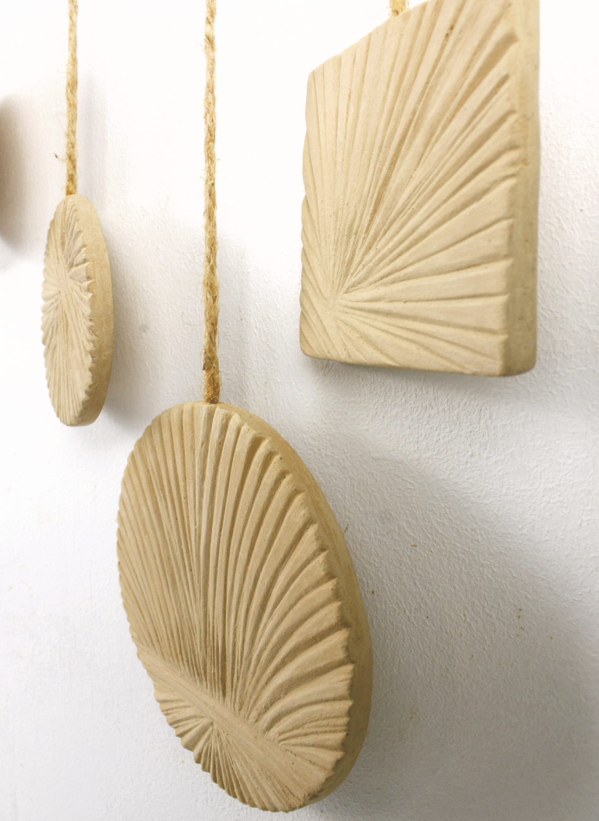 Decorative beige wall hangings with textured patterns on a white wall.