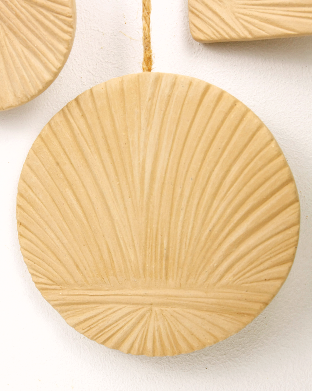 Decorative beige circular ornament with sunburst pattern on a white background